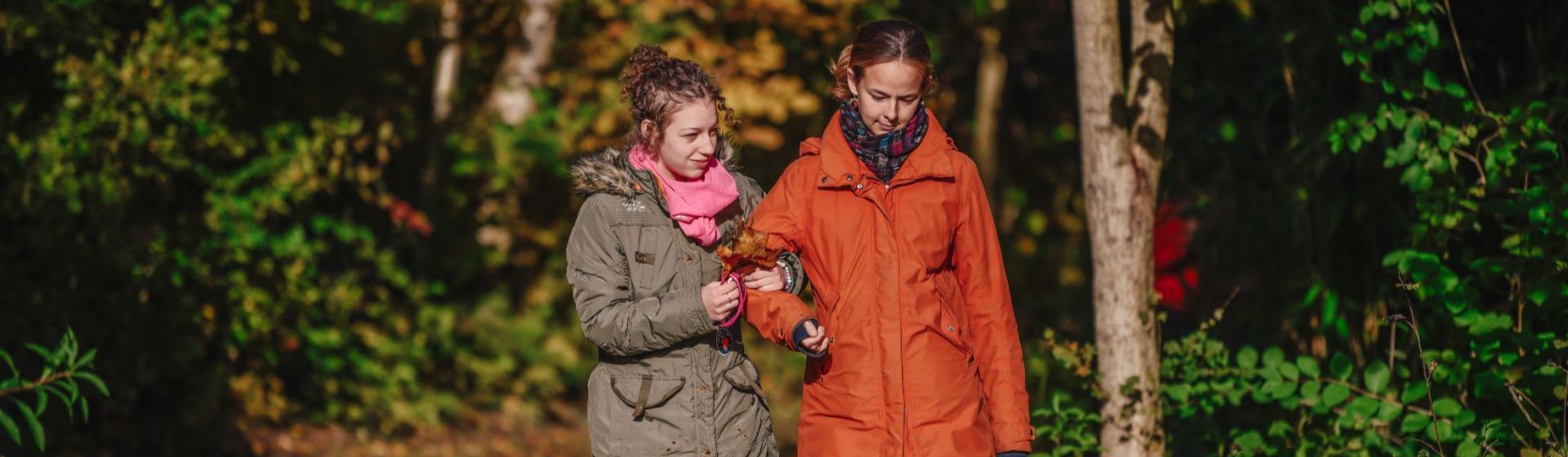 Zwei Mädchen gehen Arm in Arm im Wald spazieren