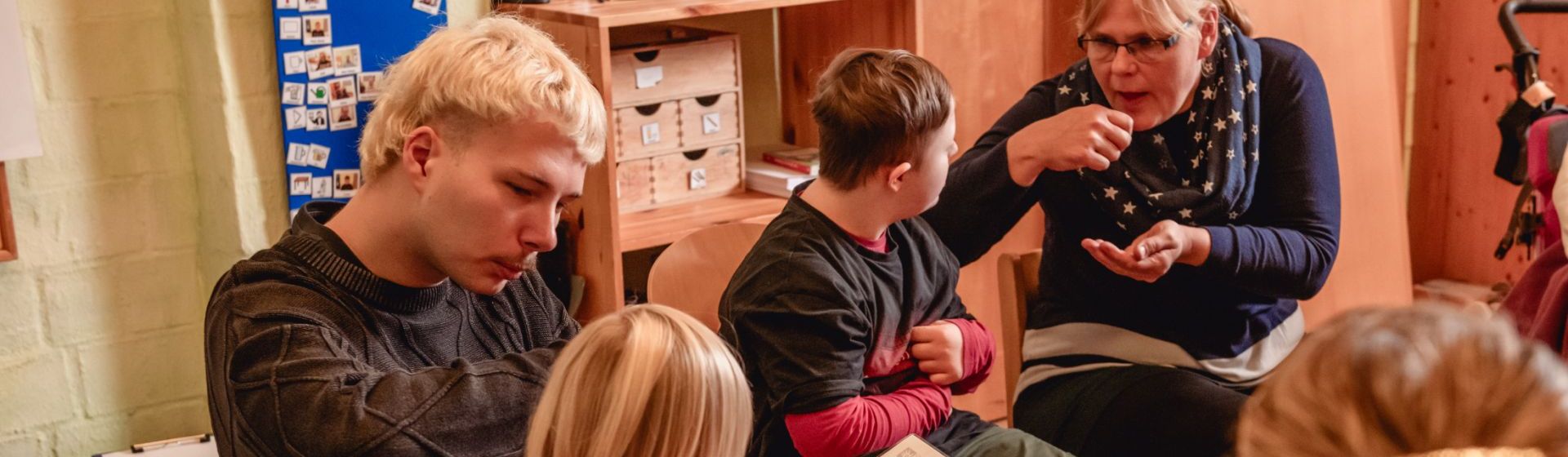 Zwei Betreuer und drei Kinder in einer Runde